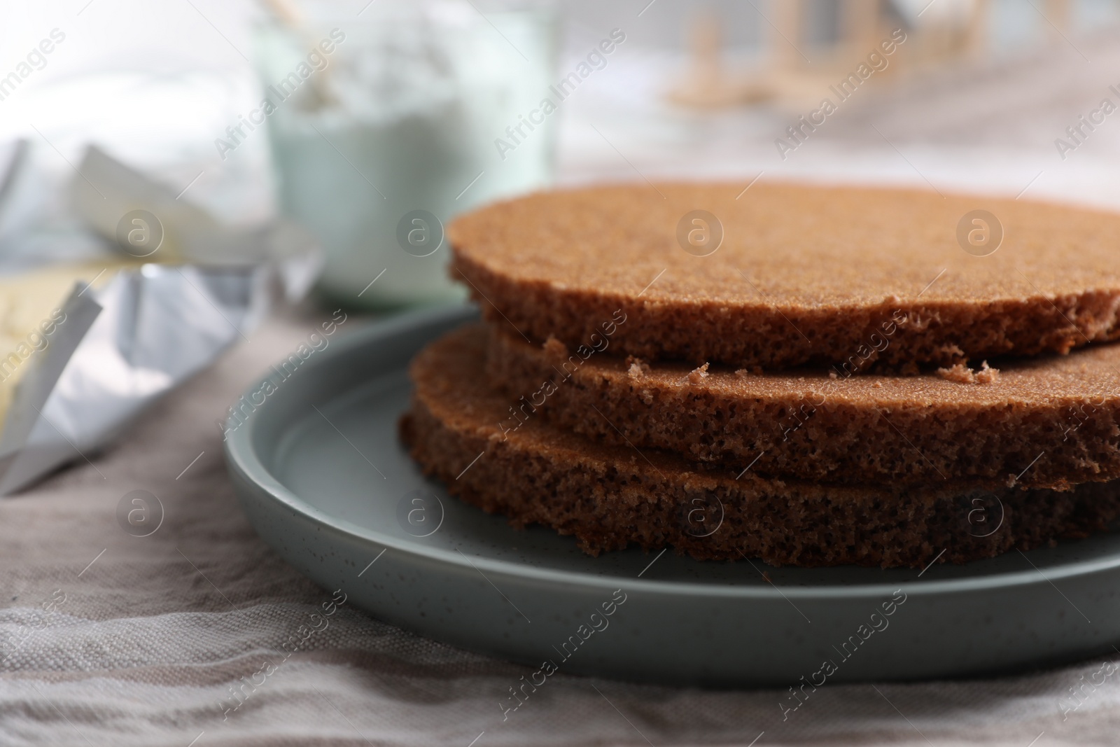 Photo of Delicious homemade sponge cakes and ingredients on grey tablecloth, closeup