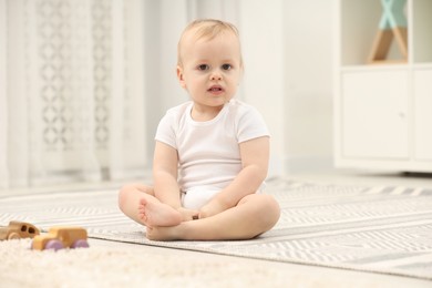 Photo of Cute little boy on rug in children's room