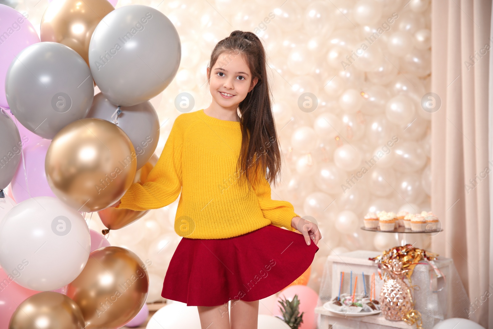 Photo of Happy little girl with balloons in beautifully decorated room at home. Birthday celebration