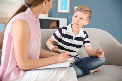 Female psychologist working with cute little boy in office