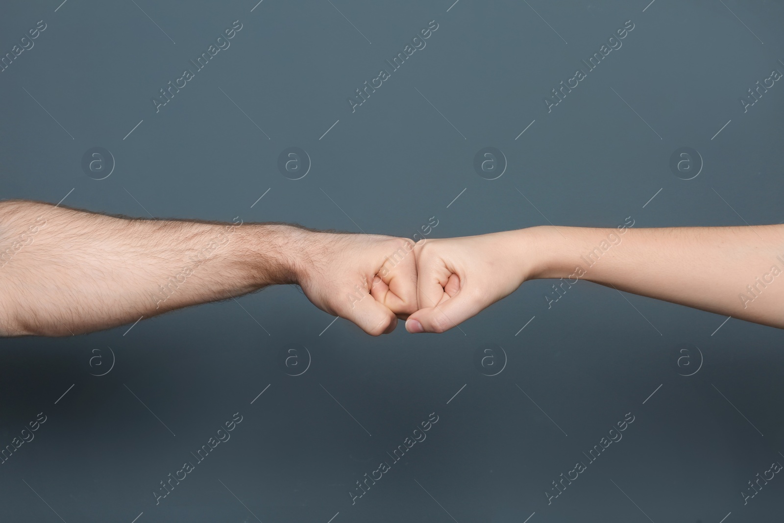 Photo of Young man and woman making fist bump on color background