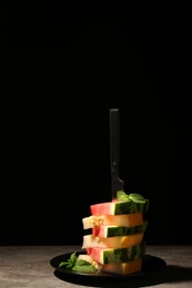 Stacked watermelon and melon slices on table against black background