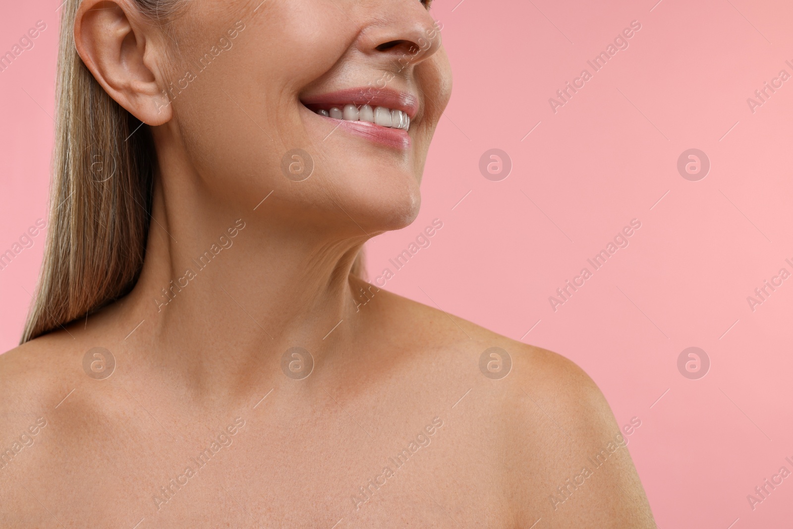 Photo of Mature woman with healthy skin on pink background, closeup. Space for text