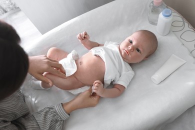 Photo of Mother changing her baby's diaper on table indoors, closeup