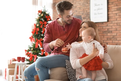 Photo of Happy couple with baby celebrating Christmas together at home