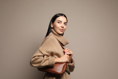 Photo of Fashionable young woman with stylish bag on beige background