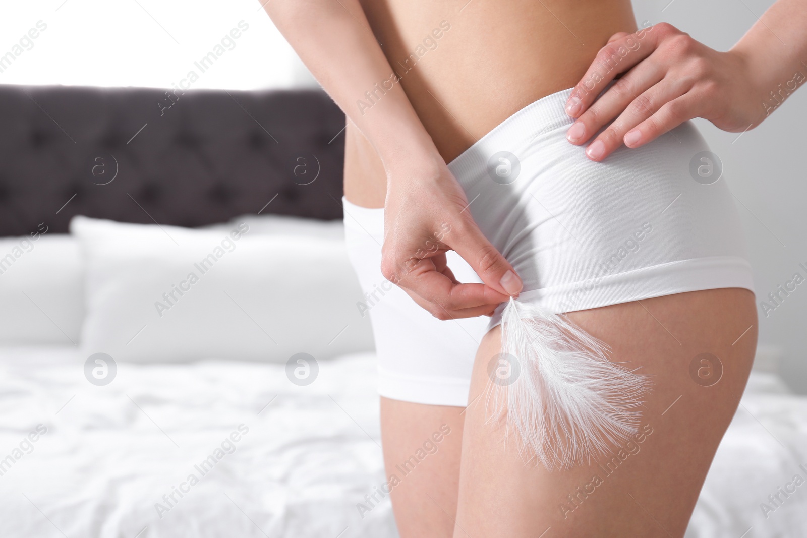 Photo of Closeup of woman touching leg with feather in bedroom, space for text. Epilation procedure