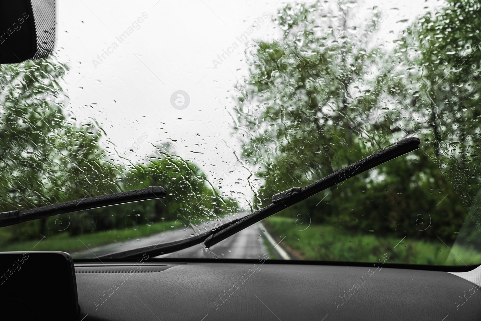 Photo of Blurred view of suburban road through wet car window. Rainy weather