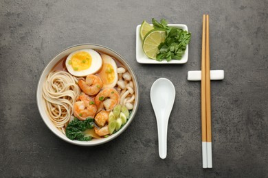 Photo of Delicious ramen with shrimps and egg in bowl served on grey table, flat lay. Noodle soup