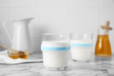 Photo of Delicious milk and honey on white marble table