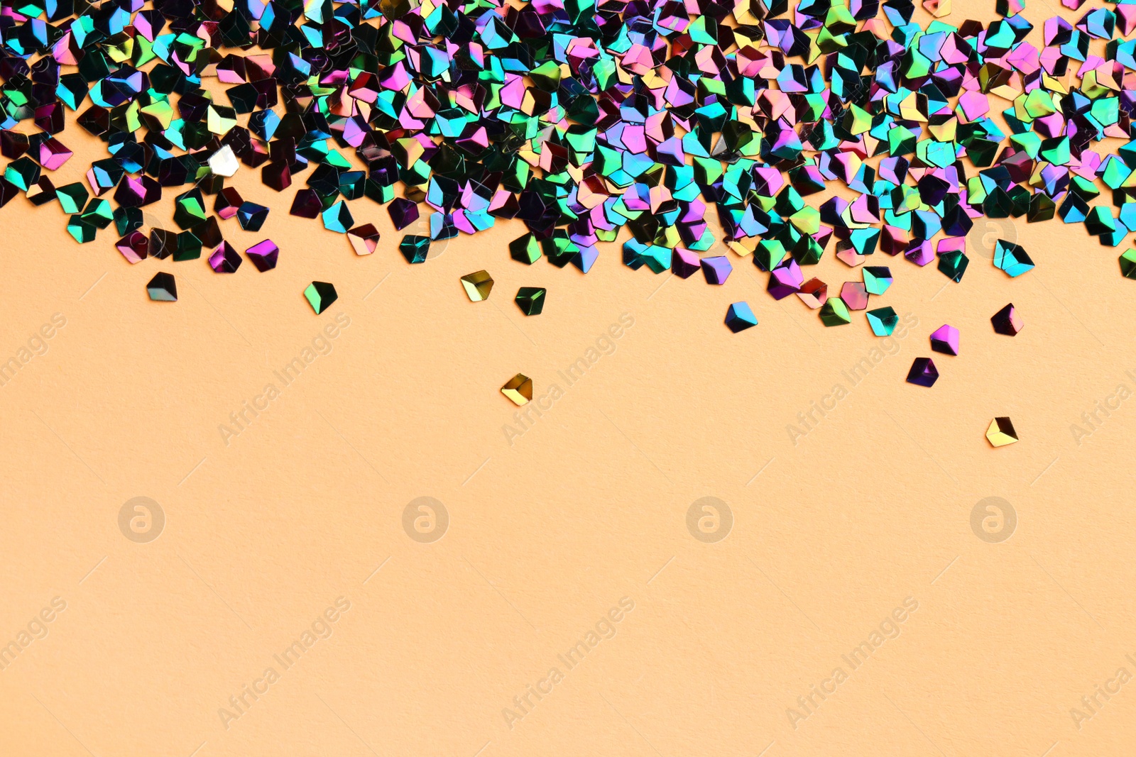 Photo of Pile of shiny glitter on beige background, space for text