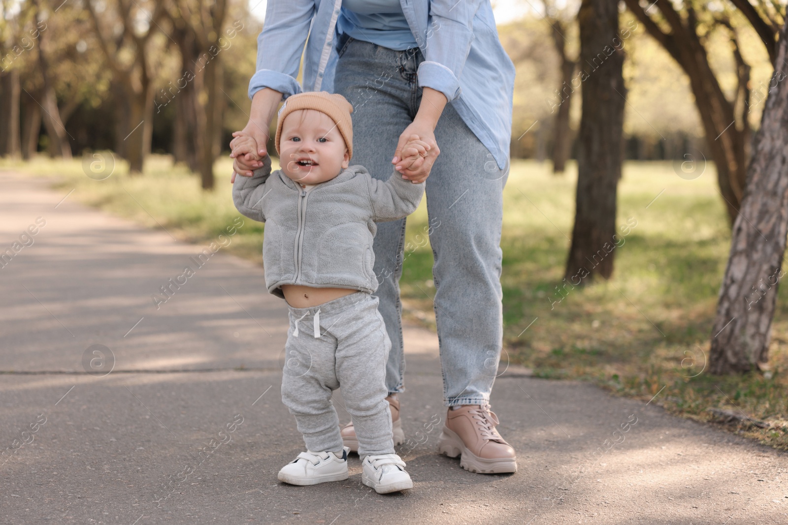 Photo of Mother teaching her baby how to walk outdoors, closeup