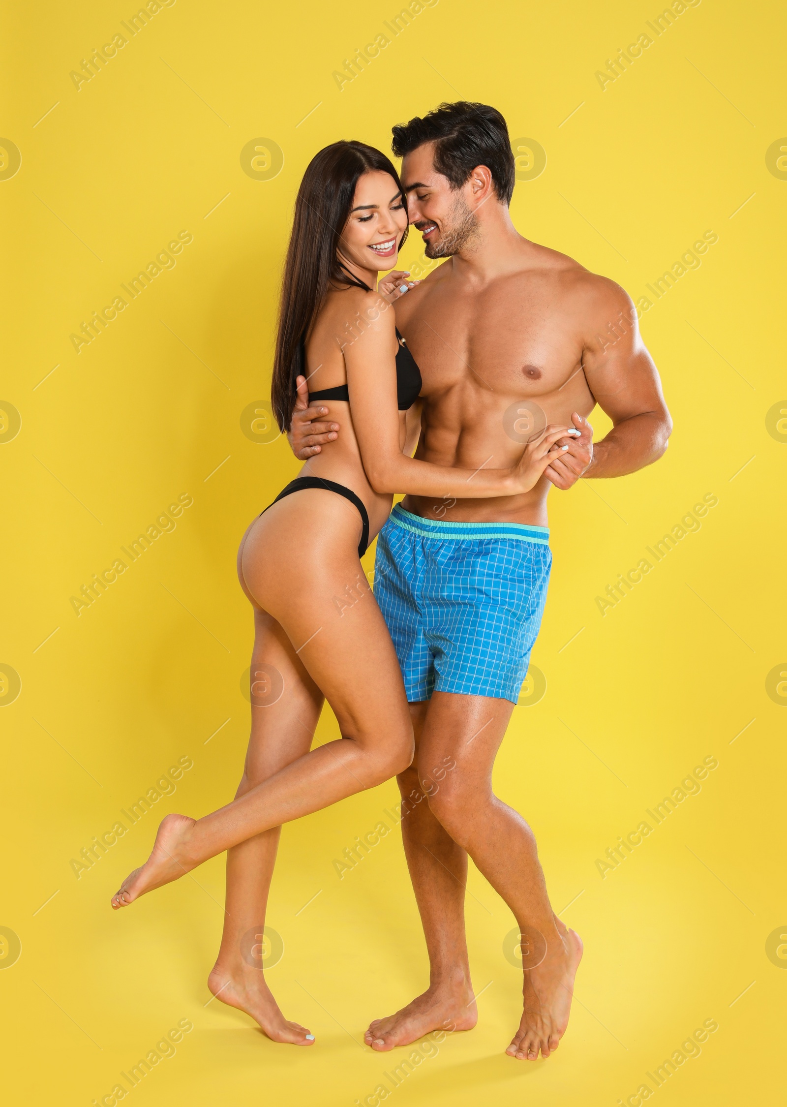 Photo of Young attractive couple in beachwear on yellow background