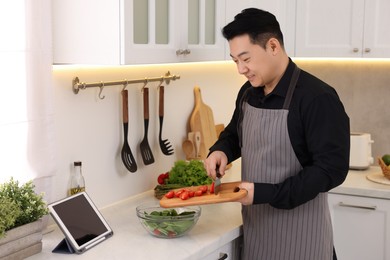 Photo of Man making fresh salad in kitchen. Cooking process