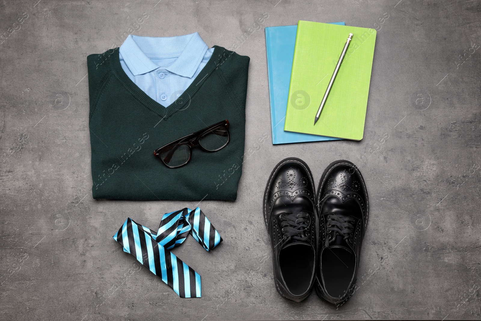 Photo of Stylish school uniform for boy and stationery on grey background, flat lay