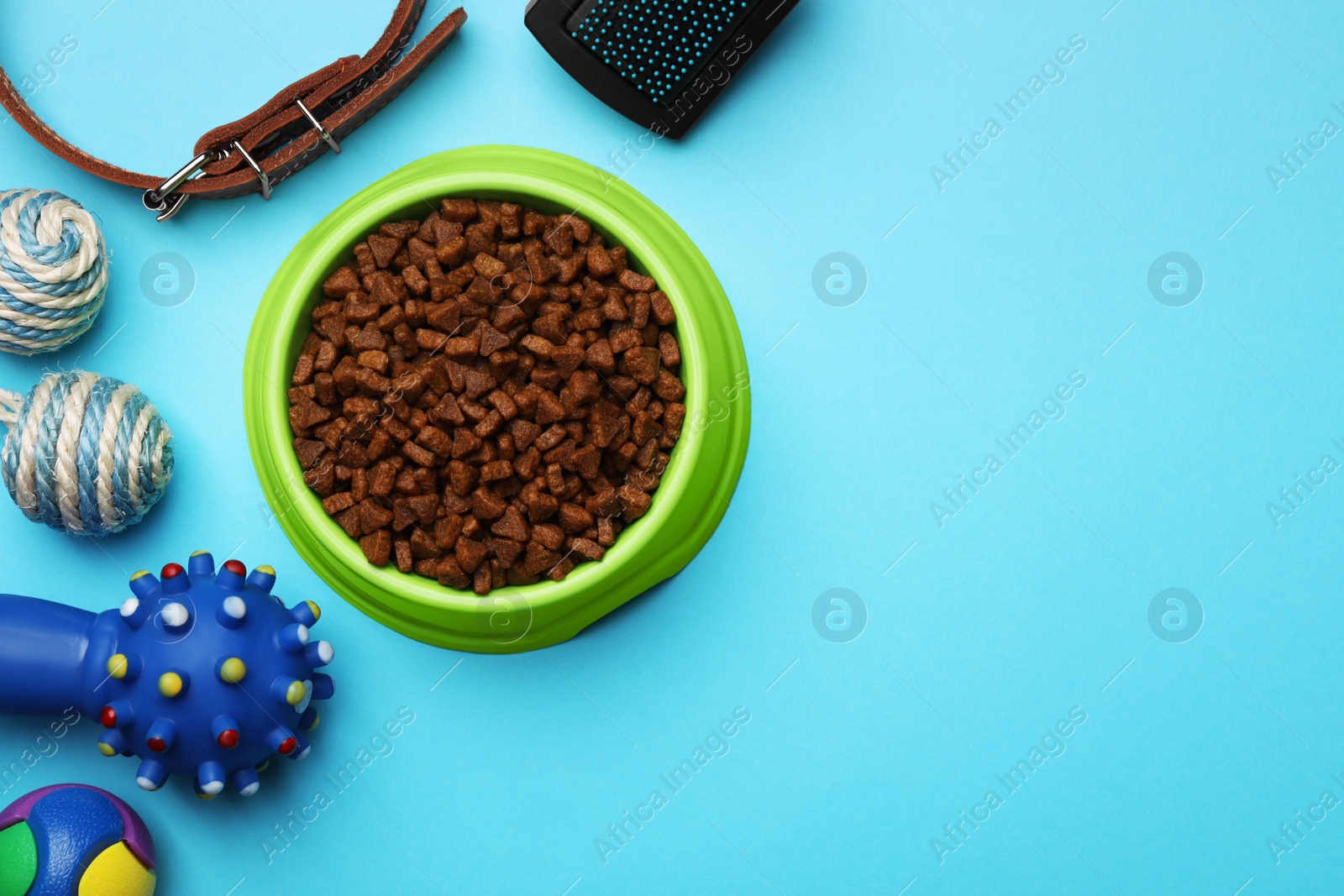 Photo of Pet toys, bowl of food and accessories on light blue background, flat lay. Space for text