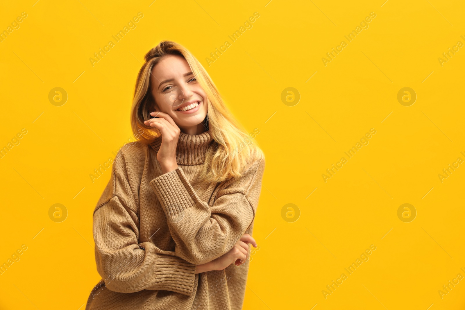 Photo of Beautiful young woman wearing knitted sweater on yellow background. Space for text