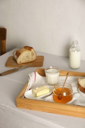 Milk, honey and bread served for breakfast on table indoors