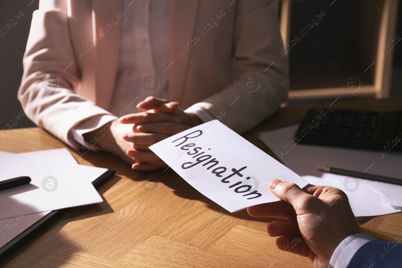 Photo of Employee giving resignation letter to boss in office, closeup