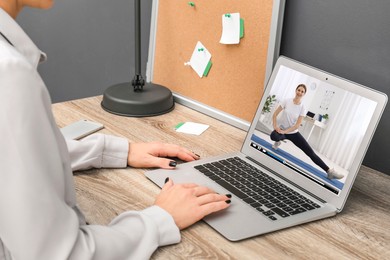 Image of Woman watching morning exercise video on laptop at table, closeup