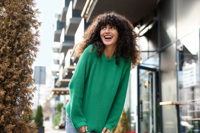 Happy young woman in stylish green sweater outdoors