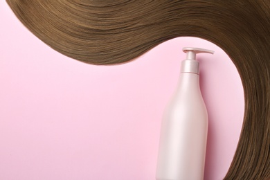 Brown straight hair and dispenser bottle on color background, flat lay. Space for text