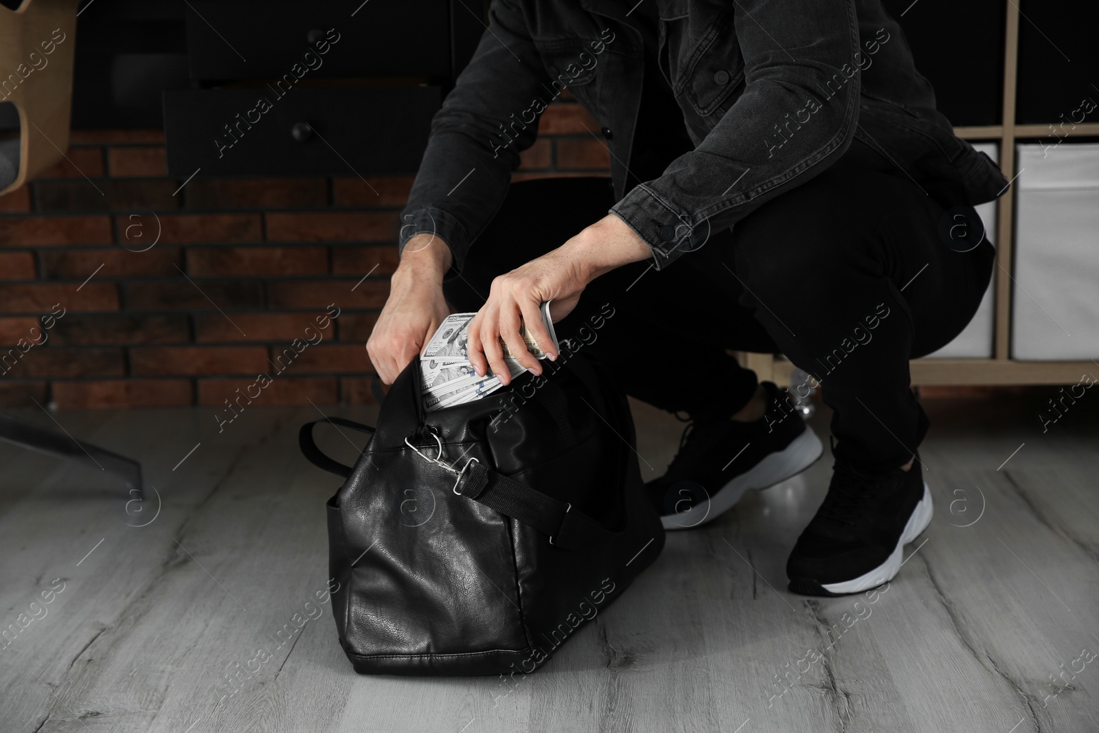 Photo of Dangerous criminal putting money in bag indoors, closeup