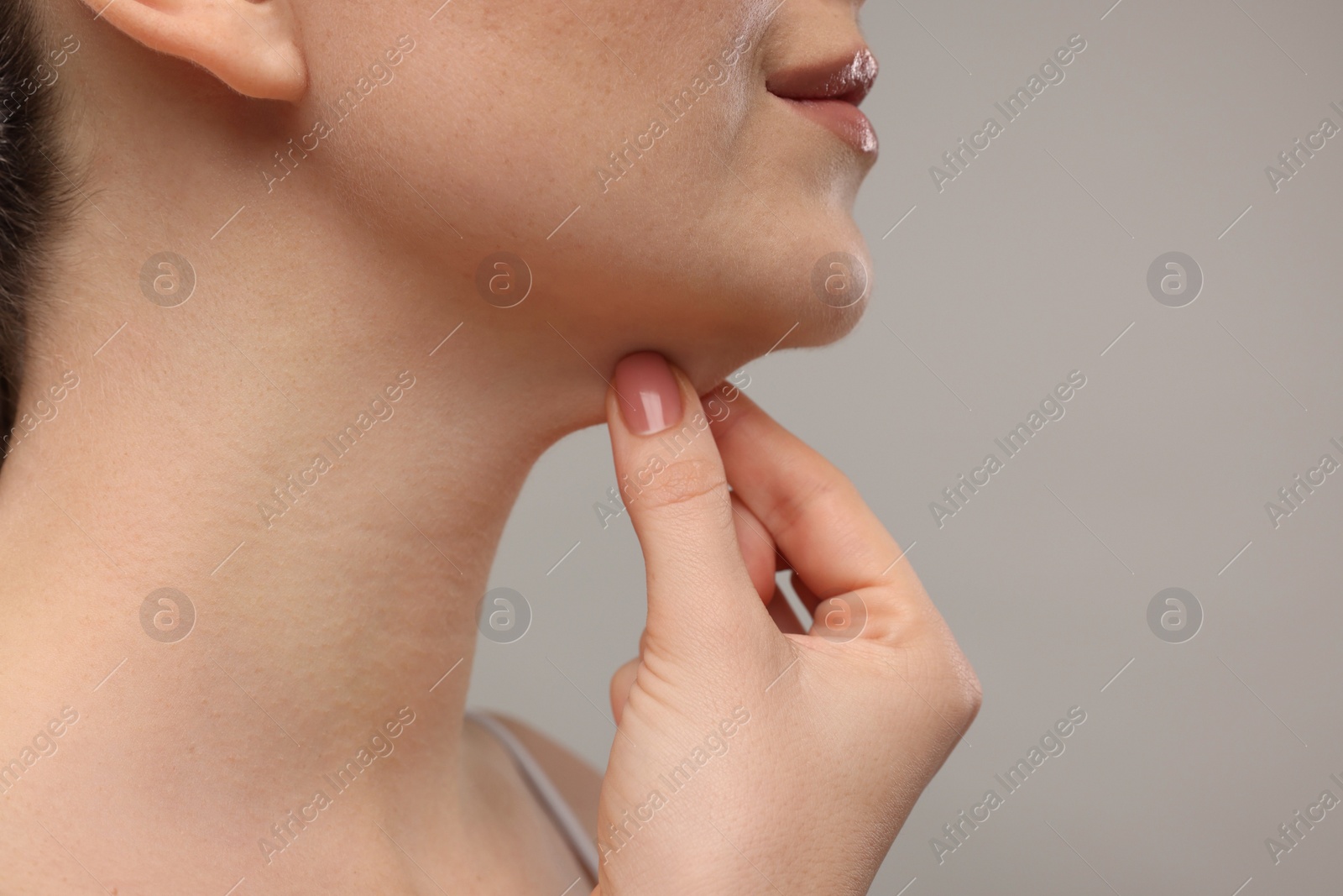 Photo of Woman touching her chin on grey background, closeup