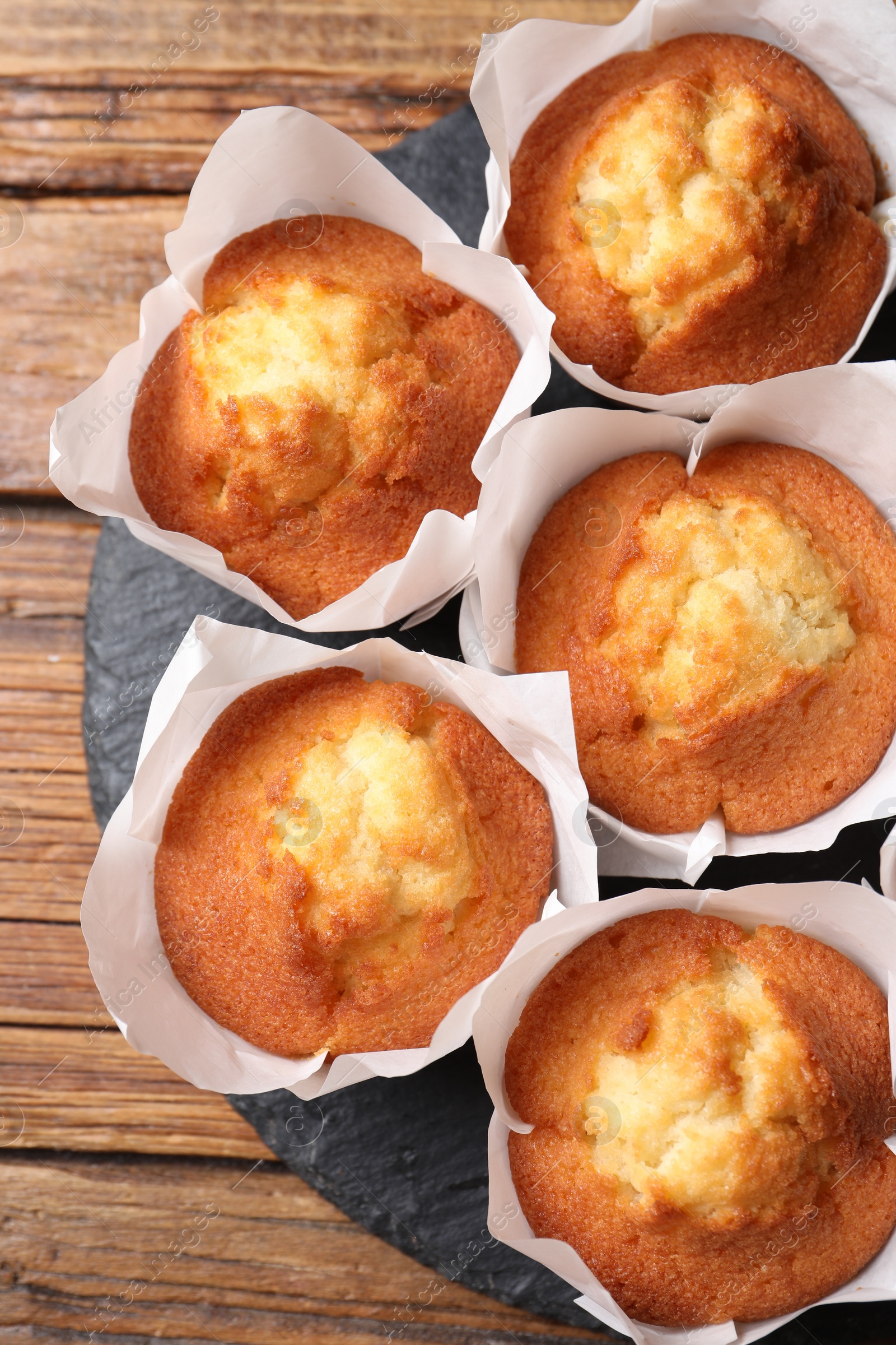 Photo of Delicious sweet muffins on wooden table, top view