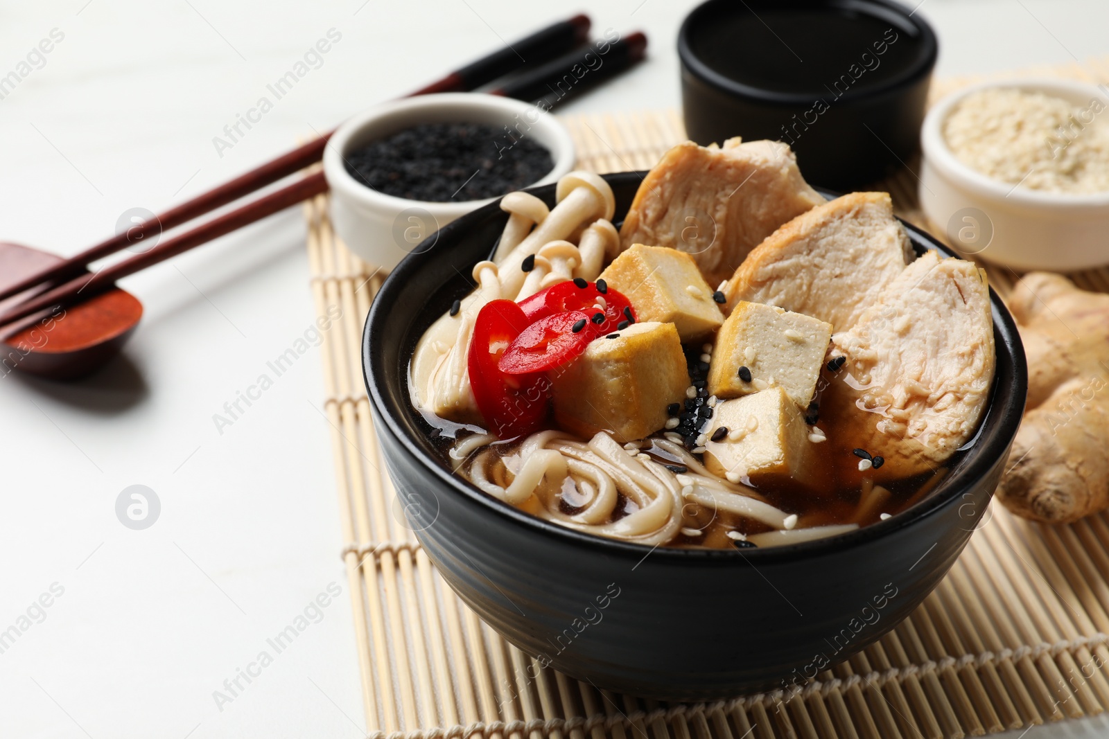 Photo of Delicious ramen served on white table, closeup. Noodle soup