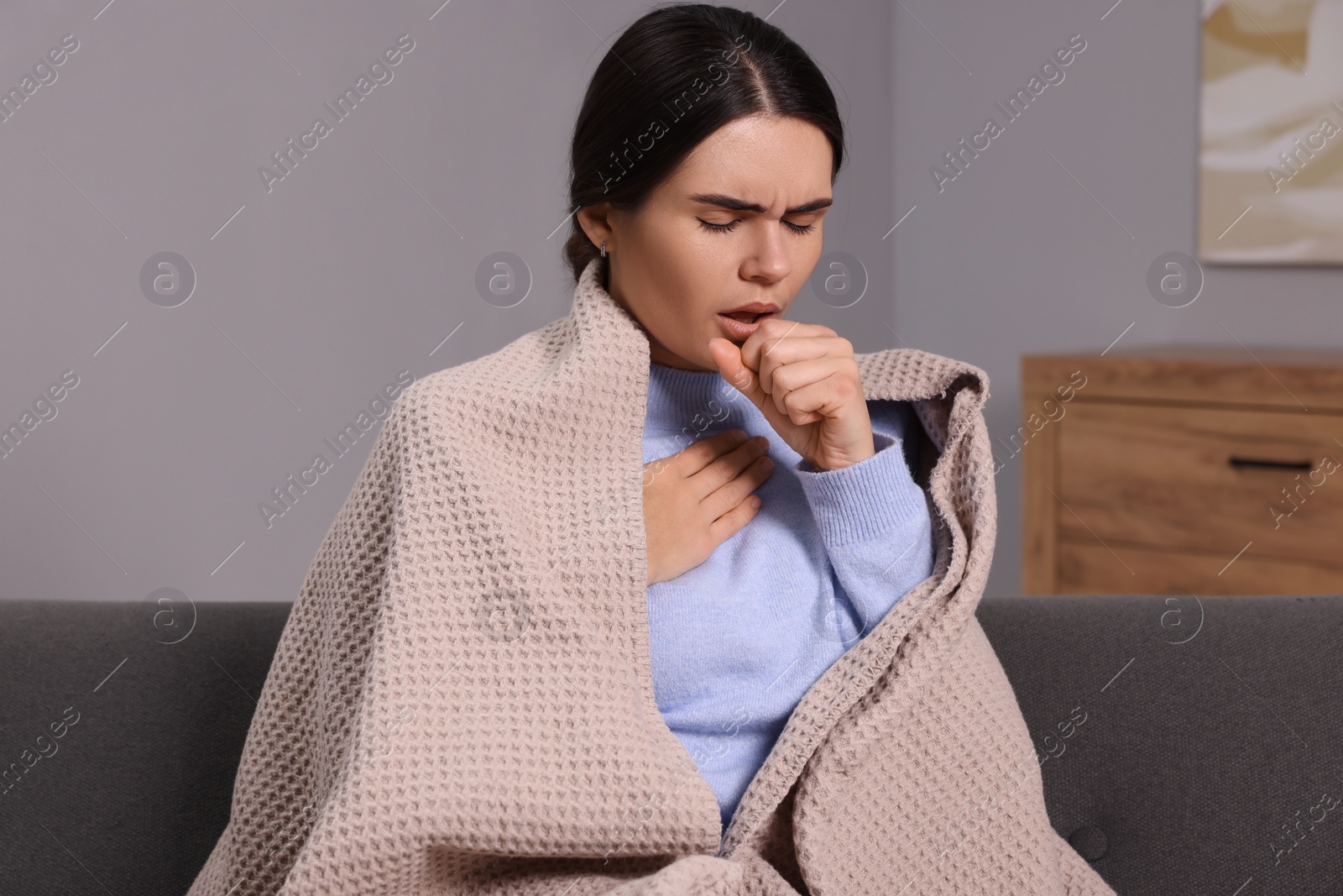 Photo of Woman coughing on sofa at home. Cold symptoms