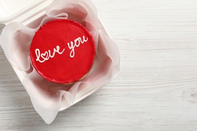 Photo of Bento cake with Love You text in takeaway box on white wooden table, top view. Space for text. St. Valentine's day surprise