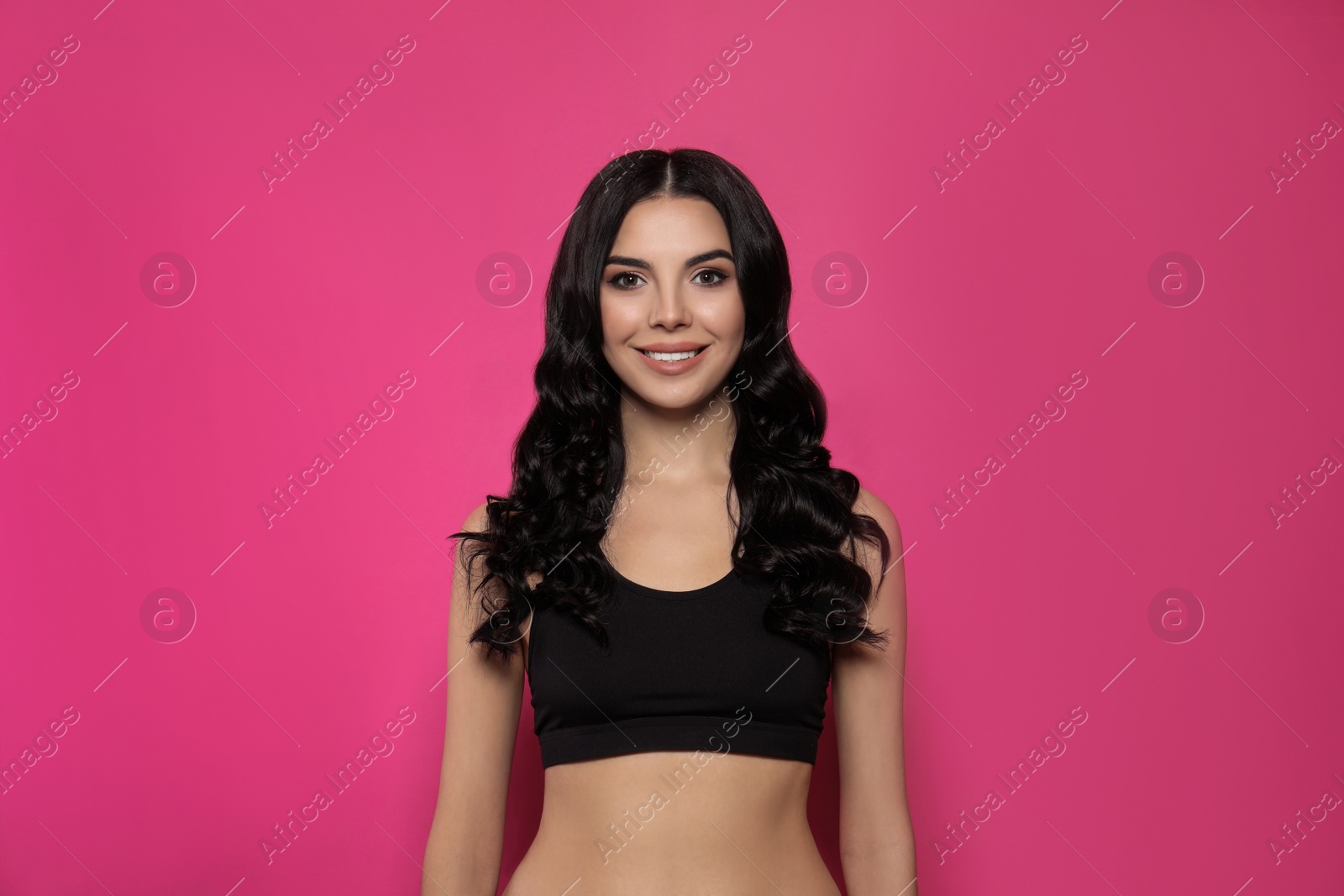 Photo of Beautiful young woman with long curly hair on pink background