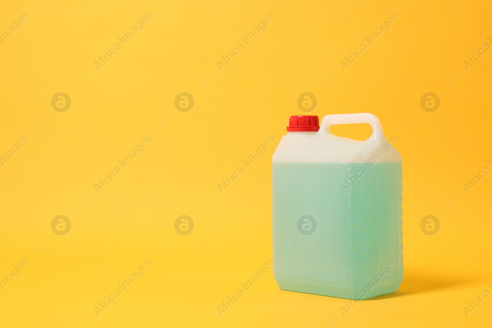 Photo of Plastic canister with green liquid on orange background. Space for text