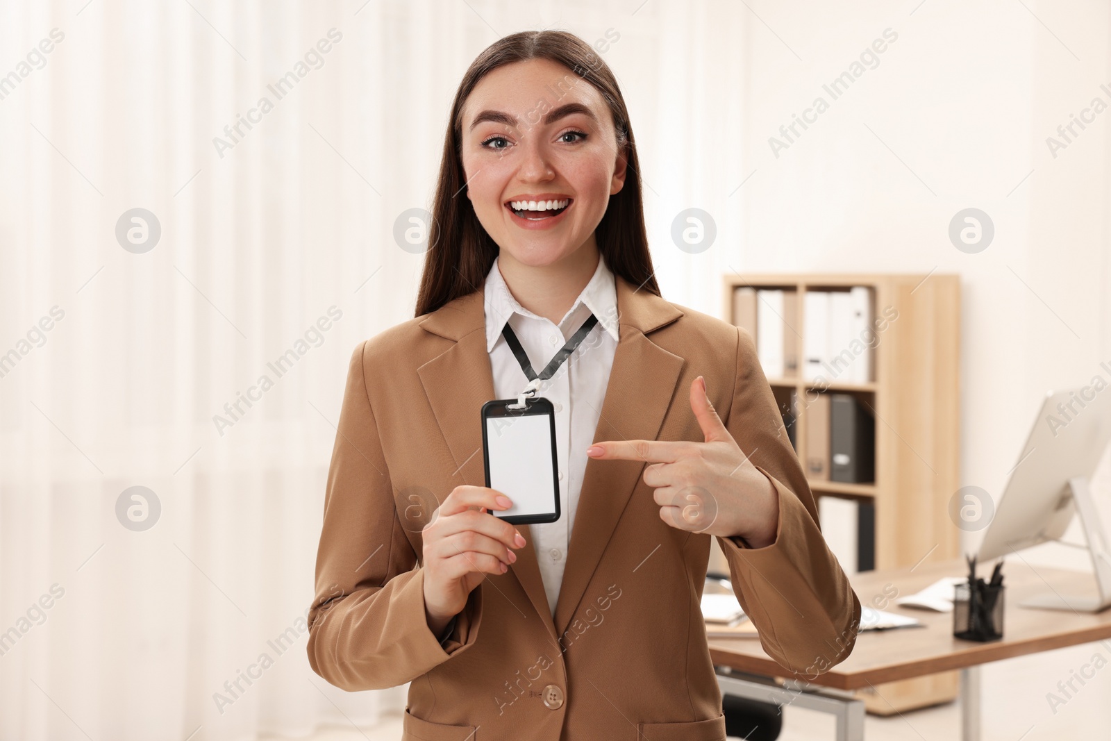 Photo of Happy woman pointing at blank badge in office