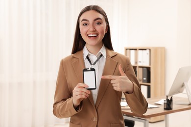 Happy woman pointing at blank badge in office