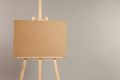 Wooden easel with blank board on grey background. Space for text