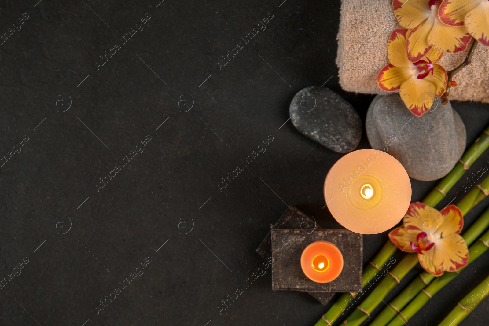 Photo of Flat lay composition with candles and spa stones on dark table. Space for text