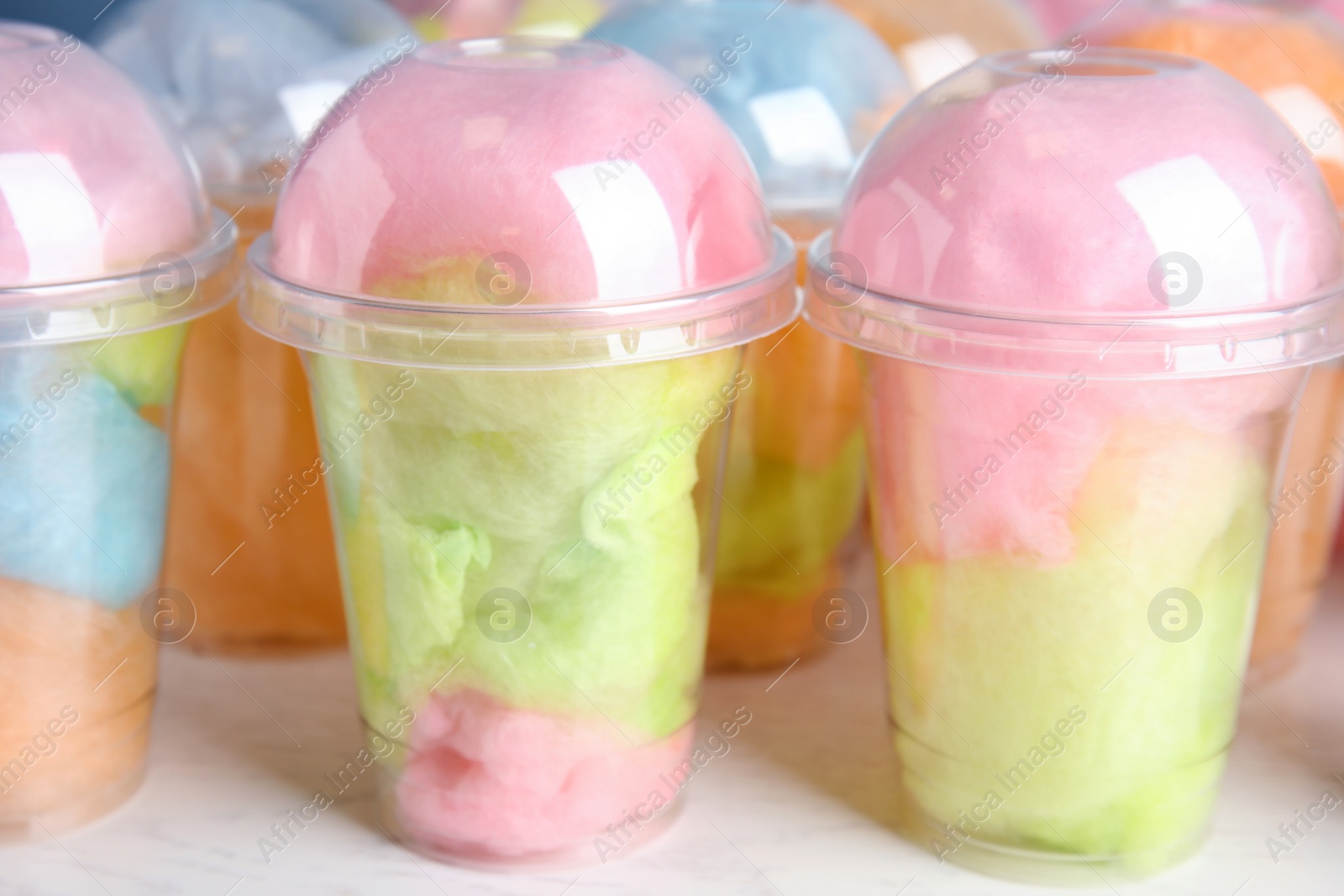 Photo of Many plastic cups with tasty cotton candies on white wooden table