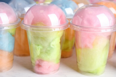 Photo of Many plastic cups with tasty cotton candies on white wooden table