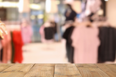 Image of Empty wooden table and blurred view of store with modern clothes