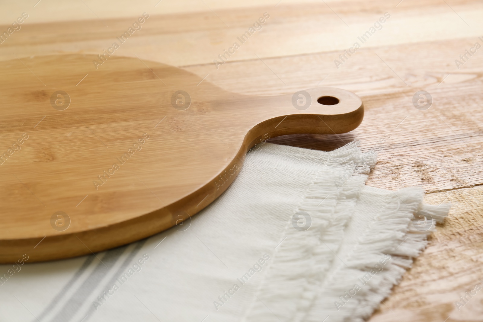 Photo of Empty wooden board and napkin on table, closeup