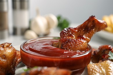 Delicious fried chicken wings served with sauce on table, closeup
