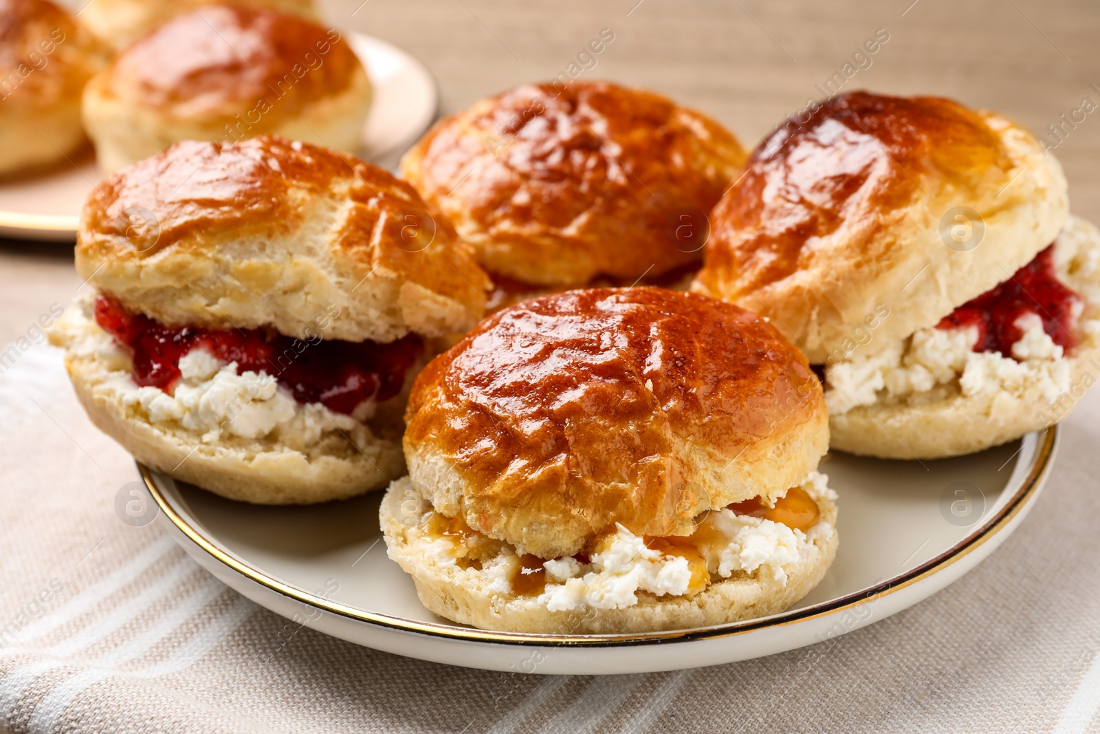 Photo of Freshly baked soda water scones with cranberry jam and butter on table, closeup