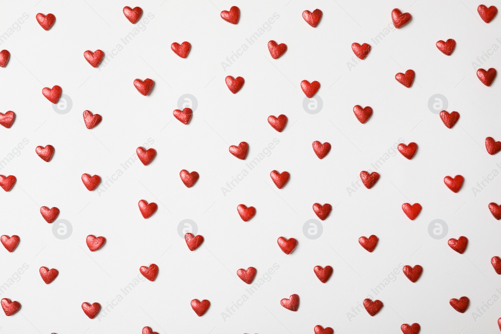 Photo of Bright heart shaped sprinkles on white background, flat lay