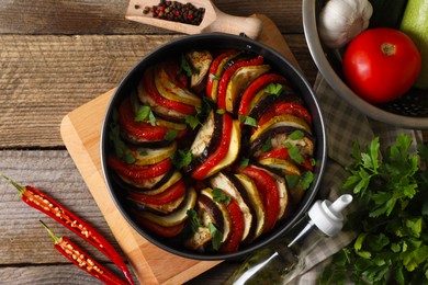 Delicious ratatouille and ingredients on wooden table, flat lay