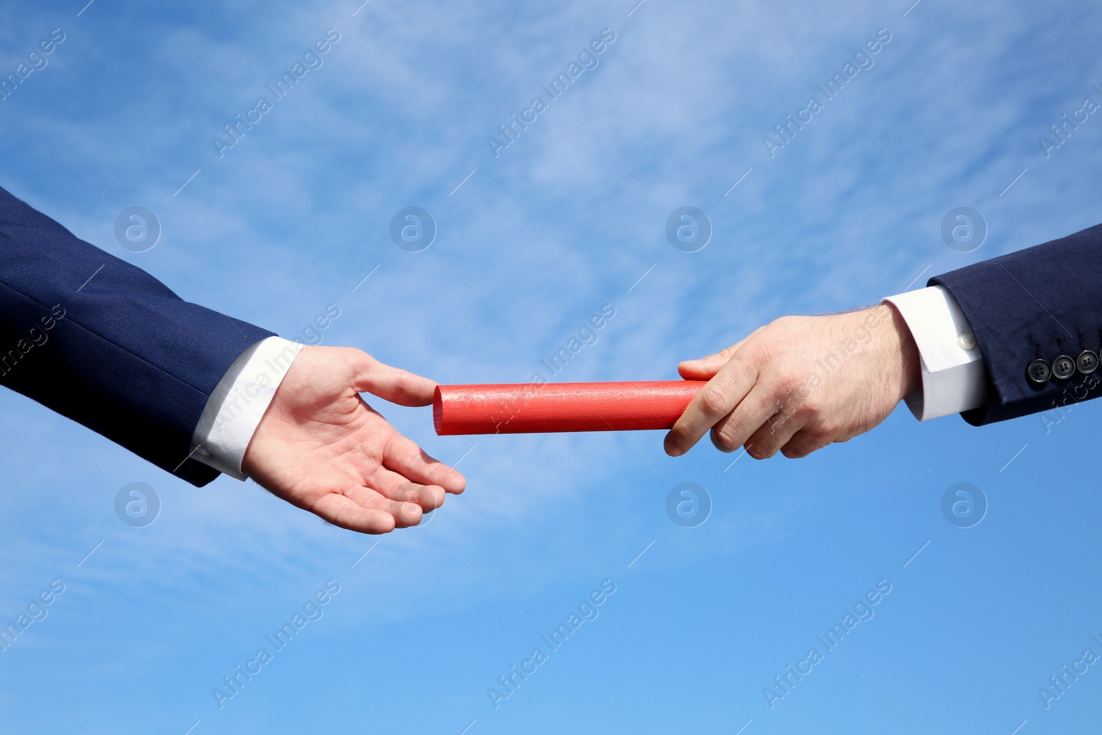 Photo of Businessman passing baton to his partner against blue sky, closeup