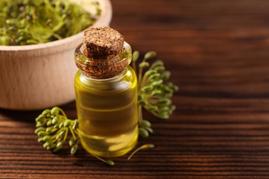 Photo of Bottle of essential oil and fresh dill on wooden table, closeup. Space for text