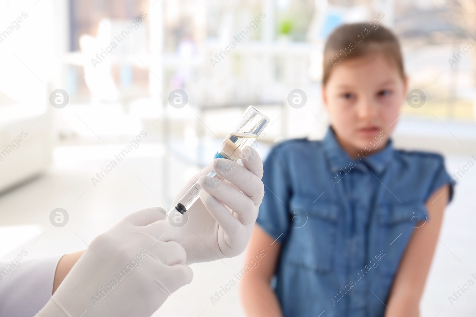 Photo of Doctor filling syringe with medicine and child on background. Vaccination day