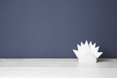 Photo of Napkin holder with paper serviettes on table against color background. Space for text